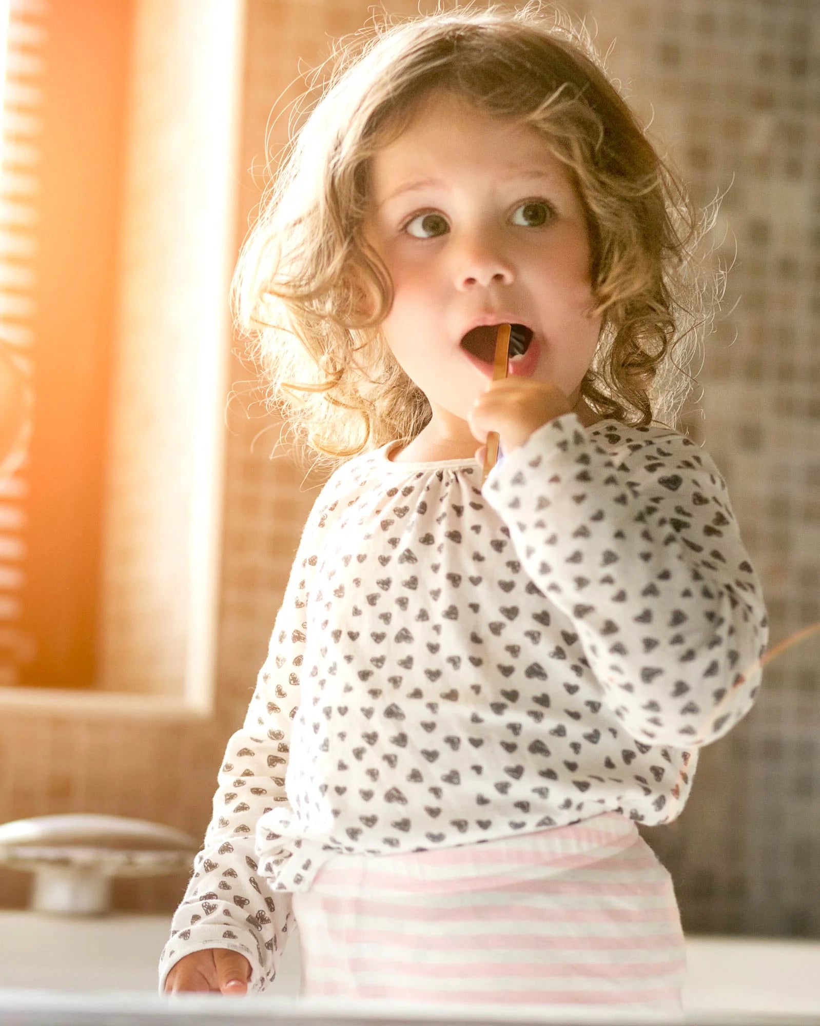 Child brushing teeth with a natural oral care product in a bright, eco-conscious bathroom setting.