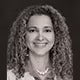 Black and white portrait of a woman with curly hair smiling, conveying a friendly and approachable demeanor.