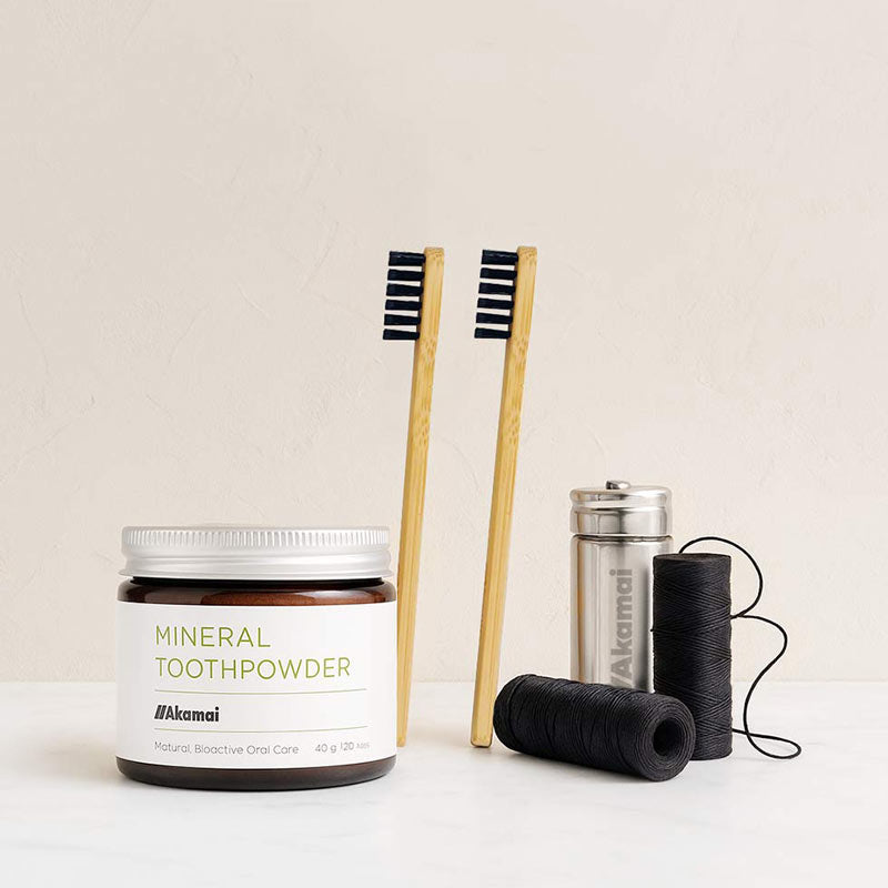 Akamai Basics mineral toothpowder with bamboo toothbrushes for holistic oral care and healthy teeth.